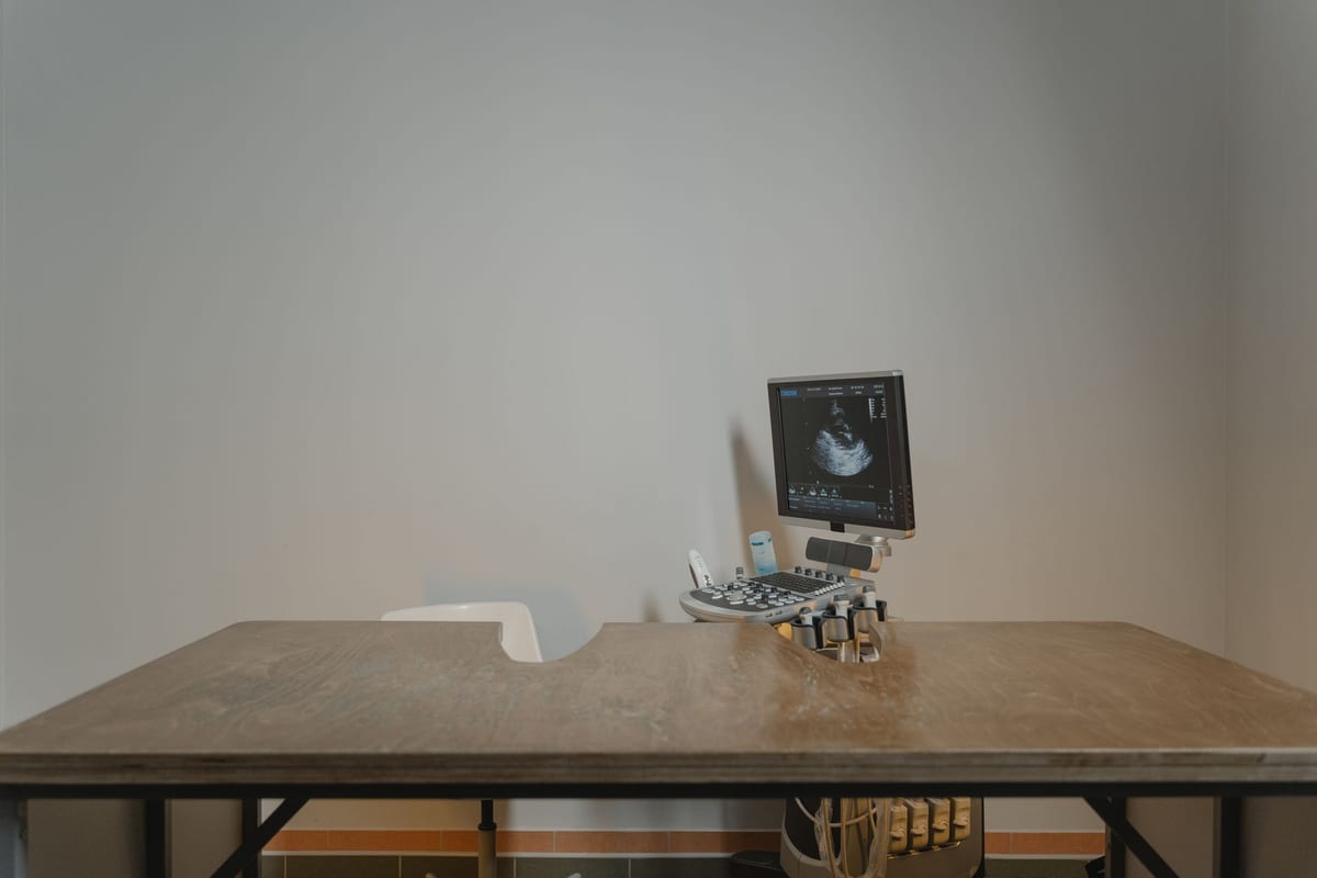 An ultrasound console beside the examination table in a consult room